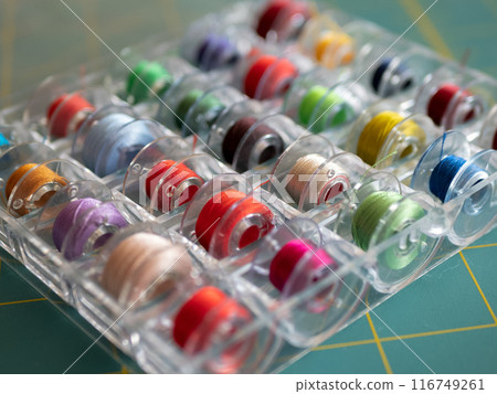 Bobbins with colored threads in the plastic box for storage. Sewing accessories concept Bobbins with colored threads in the plastic box for storage. Sewing accessories concept 116749261