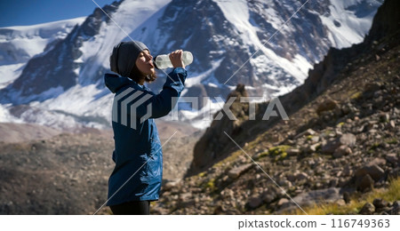 Young girl drinks water in the mountains. 116749363