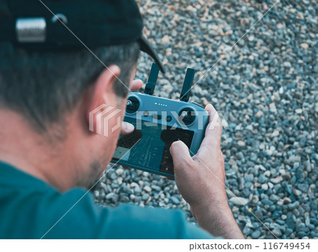 A closeup shot of a man, holding and operating a drone remote control joystick A closeup shot of a man, holding and operating a drone remote control joystick 116749454