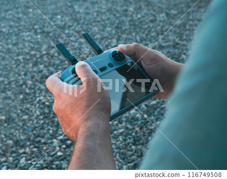 Over the shoulder shot of a man holding a drone remote control joystick 116749508