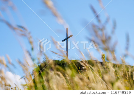 Cross is tsanding on hilltop with blurry grass 116749539