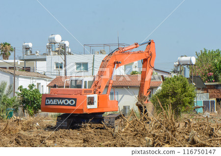 Gazeveren Cyprus 03.07.2024 - excavator uproots the roots of orange trees 116750147