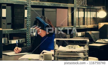 Agent extracting cryptic references found in classified records that may require further deciphering or analysis, archive room work. Law officer trying to break codes to find details. Camera A. Agent extracting cryptic references found in classified records that may require further deciphering or analysis, archive room work. Law officer trying to break codes to find details. Camera A. 116750740
