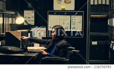 Law agent reviewing classified documents in archive room, searching for important clues from forensic evidence. Wheelchair user categorizing archived materials to facilitate investigation. Camera A. 116750765