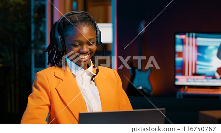 Young woman participating in online debate forums or academic competitions to learn case studies relevant to university coursework. African american girl listening to web webinar. Camera A. Young woman participating in online debate forums or academic competitions to learn case studies relevant to university coursework. African american girl listening to web webinar. Camera A. 116750767