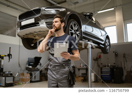 Mechanic inspecting car repair work using tablet in the garage 116750799