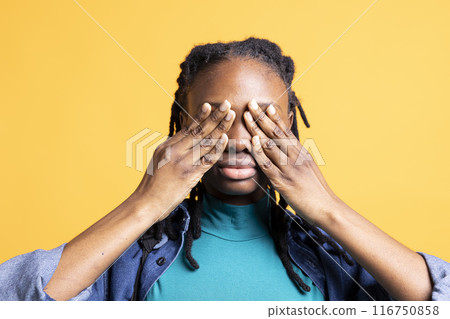 Tired BIPOC young girl covering face with palms, exhausted after long day at school. Close up shot of teenager in need of break, obstructing eyes with hand, isolated over studio background Tired BIPOC young girl covering face with palms, exhausted after long day at school. Close up shot of teenager in need of break, obstructing eyes with hand, isolated over studio background 116750858