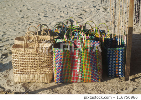 Hand Woven coconut and plastic Baskets of items for sale at the beach. 116750966
