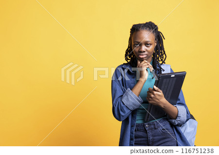 Portrait of pensive woman holding laptop, brainstorming during work shift, isolated over studio background. Employee with notebook doing thinking hand gesturing, ready to do tasks Portrait of pensive woman holding laptop, brainstorming during work shift, isolated over studio background. Employee with notebook doing thinking hand gesturing, ready to do tasks 116751238