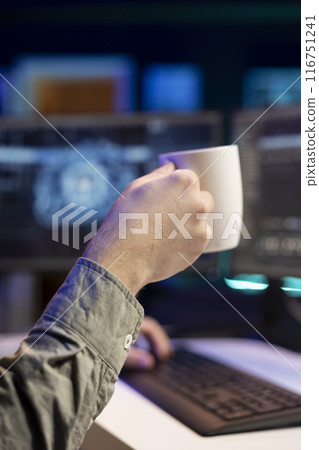 Man drinking coffee and updating artificial intelligence neural networks, writing binary code script. IT professional upgrading high tech AI, enjoying hot beverage, close up 116751241