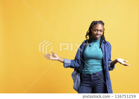 Uncaring woman doing shrugging shoulders gesture, showing indifference and apathy. Careless BIPOC person doing nonchalant indifferent hand gesturing, isolated over studio background 116751259