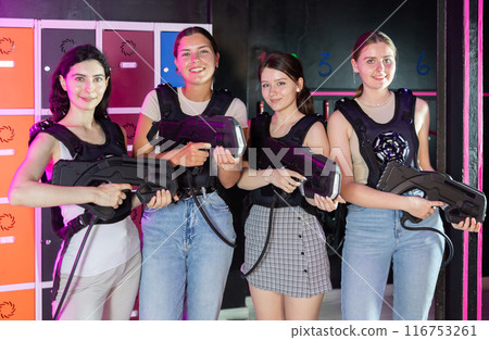 Four cheerful and happy girls pose in locker room before laser tag match. 116753261