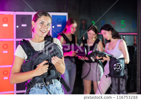 Cheerful and happy girl pose in locker room before laser tag match. Cheerful and happy girl pose in locker room before laser tag match. 116753288