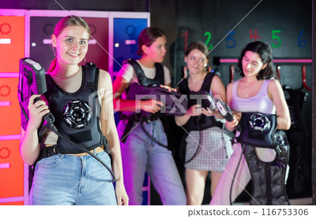 Cheerful and happy girl pose in locker room before laser tag match. Cheerful and happy girl pose in locker room before laser tag match. 116753306