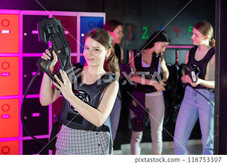 Cheerful and happy girl pose in locker room before laser tag match. 116753307