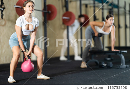 Young woman training with kettlebell in gym 116753308