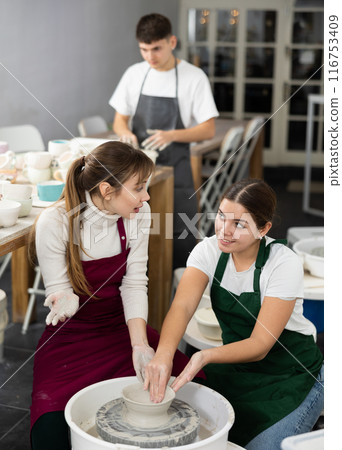 Two young women sculpt product on potter's wheel 116753409