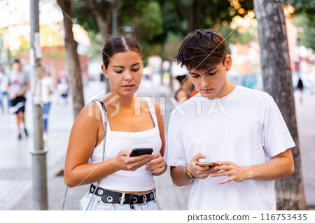 Young couple using smartphones while walking 116753435