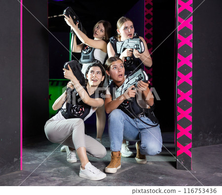 Smiling girlfriends playing laser tag game with colored laser 116753436