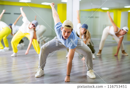 Expressive teenage boy dancer having group training in dance hall 116753451