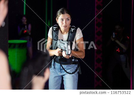 Young lady having fun playing lasertag in labyrinth Young lady having fun playing lasertag in labyrinth 116753522