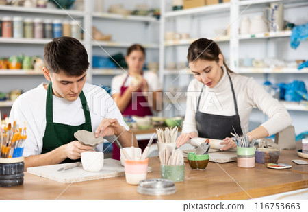 Young woman and young man making pottery Young woman and young man making pottery 116753663