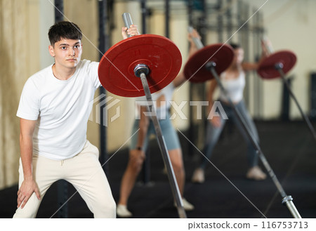 Young guy training with barbell with one arm 116753713