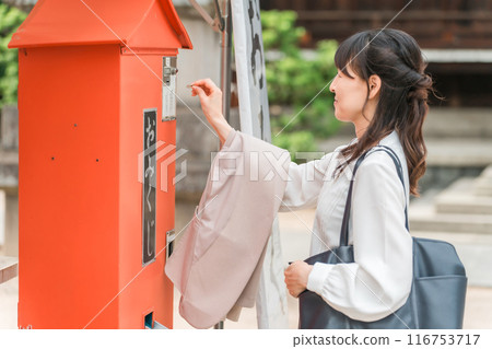 Asian woman drawing a fortune at a shrine Asian woman drawing a fortune at a shrine 116753717