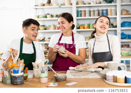 Two young women and young man making pottery Two young women and young man making pottery 116753851
