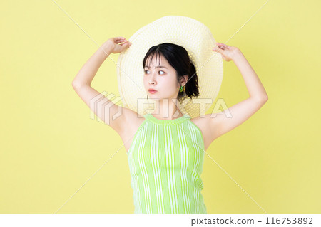 夏季圖像，黃色背景，一位拿著草帽的年輕女子的肖像 116753892