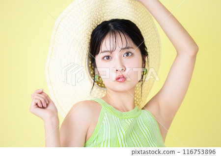 Summer image Yellow background Portrait of a young woman holding a straw hat Summer image Yellow background Portrait of a young woman holding a straw hat 116753896