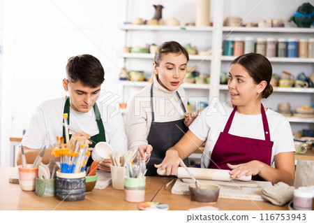 Two young women and young man making pottery Two young women and young man making pottery 116753943