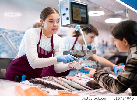 Woman seller of fish advises buyer to buy hake fresh fish 116754040