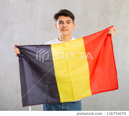 Smiling young guy holding Belgium flag Smiling young guy holding Belgium flag 116754079