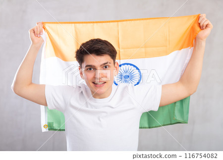 Happy young man holding flag of India against unicoloured background 116754082
