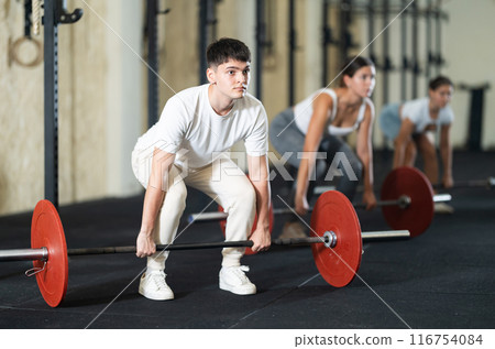 Young guy lifts barbell in gym 116754084