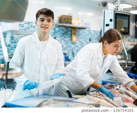 Positive shop assistants in work clothes posing in fish store 116754101