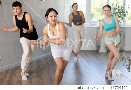 Group of young people dancing indoors. 116754121