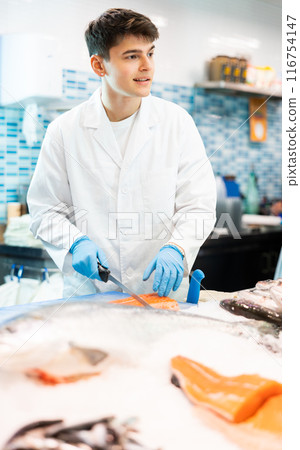 Proficient salesman cutting fish fillet in fish store Proficient salesman cutting fish fillet in fish store 116754147