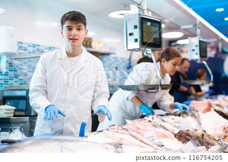 Positive shop assistants in work clothes posing in fish store Positive shop assistants in work clothes posing in fish store 116754205