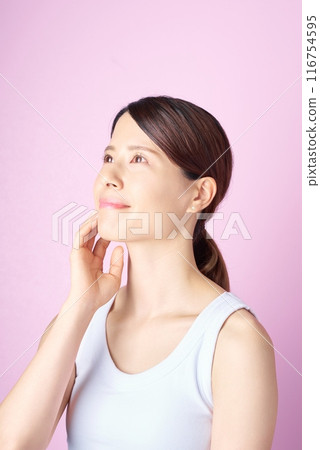 一位女士檢查她的皮膚狀況和粉紅色背景 116754595