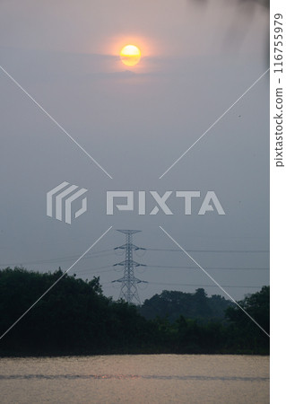 high voltage electricity tower on the hill behind the lake 116755979