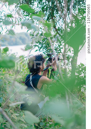 a male photographer in the wild with his camera with leaves foreground a male photographer in the wild with his camera with leaves foreground 116756065
