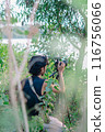 a male photographer in the wild with his camera with leaves foreground 116756066