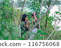 a male photographer in the wild with his camera with leaves foreground 116756068