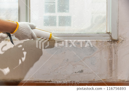 Construction worker using silicone sealant caulk for repair leaked inside window frame. Construction worker using silicone sealant caulk for repair leaked inside window frame. 116756893