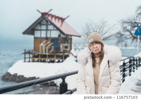 Woman tourist sightseeing Kansa Shrine and Lake Tazawa in winter. Traveler travel in Semboku city, Akita Prefecture, Japan. Landmark for tourist attraction in Tohoku region. Japan travel and vacation 116757103