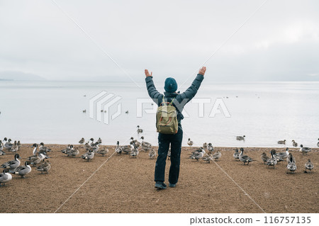 Woman tourist travel Lake Inawashiro in winter, Traveler sightseeing Ducks, Swan and bird in Fukushima Prefecture, Tohoku Region, Japan. Landmark travel and adventure vacation concept 116757135