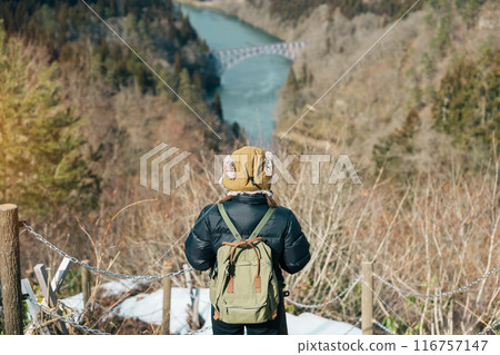 Woman tourist sightseeing View of Japan local train with Tadami river and bridge. Traveler travel at Tadami Railway Line in Mishima Machi, Aizu, Fukushima Prefecture, Japan. Landmark and iconic spot 116757147