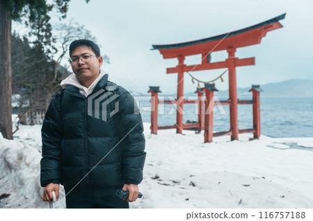 man  tourist sightseeing Japanese Torii gate  Shrine and lake Tazawa. Traveler travel in Semboku city, Akita Prefecture, Japan. Landmark for tourist attraction in Tohoku. Japan travel and vacation 116757188